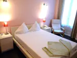 Comfort Double room bed with green throw at the foot and armchair by the curtained window